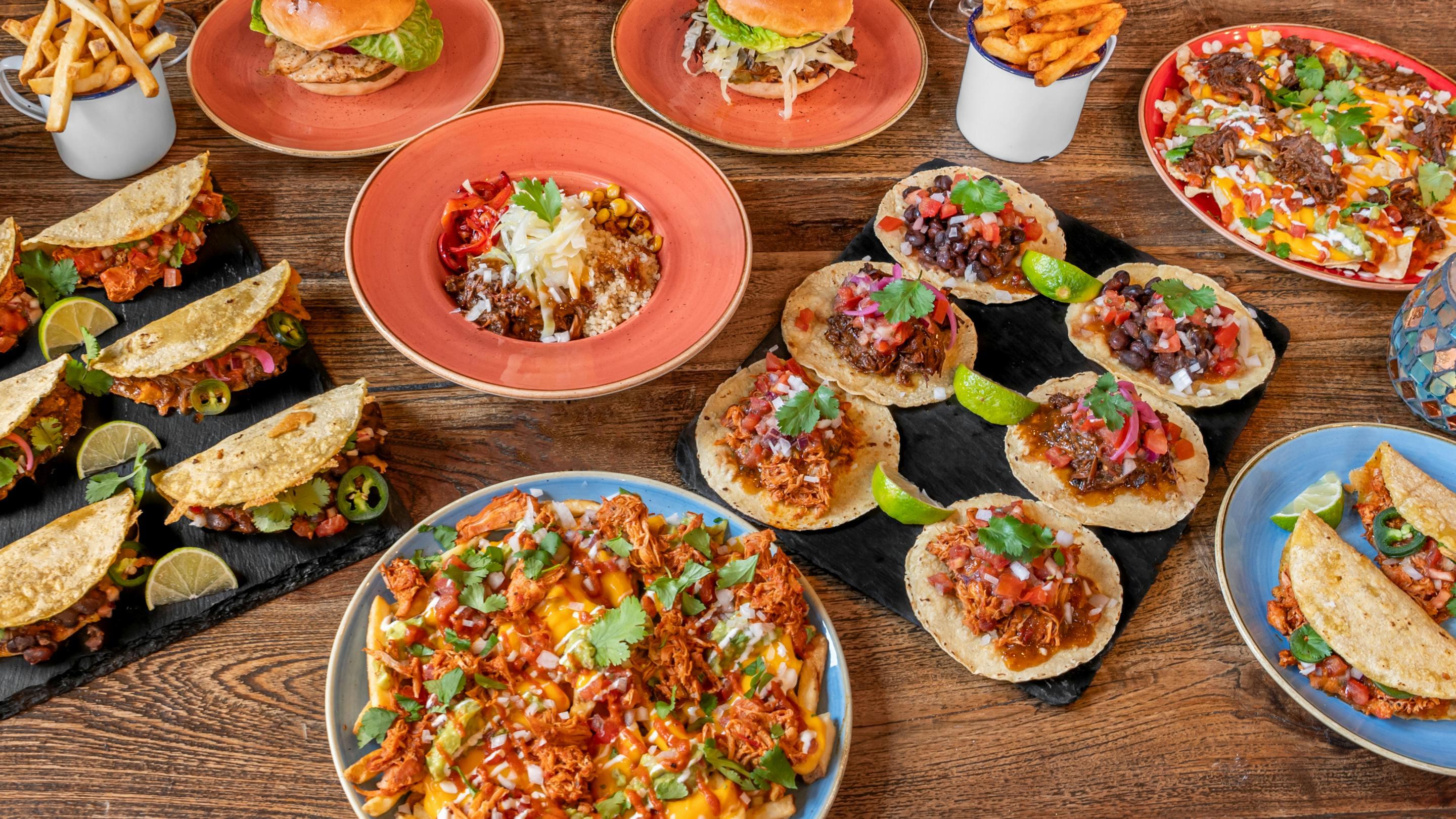 Tasty and colourful nachos and tacos on different plates across variety of colours